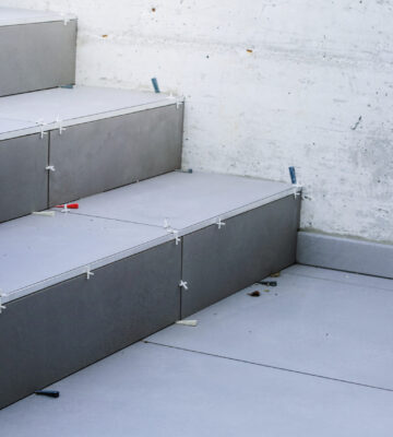 Laying new tiles on a concrete steps outside of a building